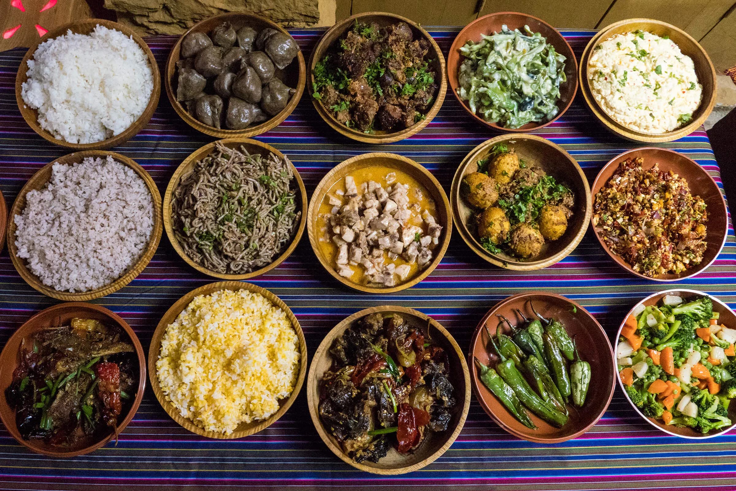 A Bhutanese table — ema datshi, red rice, kewa datshi and the dishes of the valley